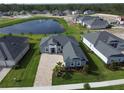 Aerial view of home showing landscaping, a nearby lake with fountain, and other homes in the community at 1000 Megano Blvd, Deland, FL 32724