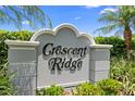 Landscaping surrounds the community sign for Crescent Ridge against a backdrop of palm trees and blue skies at 10800 Crescent Ridge Loop, Clermont, FL 34711