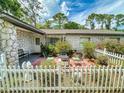 View of quaint outdoor patio with white picket fence, mature plants, outdoor seating, and stone statues at 1229 Jeffery Dr, Port Orange, FL 32129