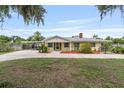 Quaint yellow single-story home with covered parking, lush landscaping, and a charming front entrance at 1411 Cliff Ave, Eustis, FL 32726