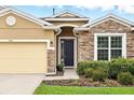 Attractive home exterior showcasing a stone facade, two-car garage and a well-maintained lawn at 1444 Daystar Ln, Deltona, FL 32725