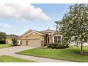 Inviting home featuring a two-car garage, stone accents, landscaping and a flowering shade tree at 1444 Daystar Ln, Deltona, FL 32725