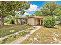 Charming single-story home with a walkway leading up to a covered porch, shaded by a large tree at 1610 Brady Dr, Deltona, FL 32725
