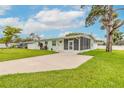 Light green home with a concrete driveway, green grass lawn and a screened-in porch at 203 Fox Pl, Port Orange, FL 32127