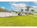 View of the front of the light green house with a white fence and a lush green lawn at 203 Fox Pl, Port Orange, FL 32127