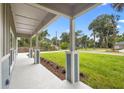 Covered front porch with decorative columns, green lawn, and landscaping at 349 Baker Ave, Lake Helen, FL 32744