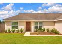 View of home exterior showcasing a brown door, landscaping, and large front windows with neutral siding at 6 Laurel Pass Ct, Ocala, FL 34480