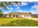 Beautiful exterior of home featuring a green lawn, landscaping, brown door, and an attached two-car garage at 6 Laurel Pass Ct, Ocala, FL 34480