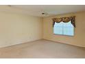 Spacious bedroom with neutral carpet, ceiling fan, and a large window dressed with floral valance at 733 E Ohio Ave, Deland, FL 32724