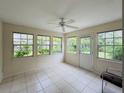 Bright sunroom with large windows, tile flooring, ceiling fan, and a door leading to the backyard at 733 E Ohio Ave, Deland, FL 32724