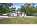 Beautifully landscaped front yard showcasing a modern, stucco home with arched windows and a circular driveway at 940 Glenwood Rd, Deland, FL 32720
