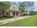 View of a tan two-story townhome showcasing a well-maintained landscape with a concrete pathway at 944 Regatta Bay Dr # 12-102, Orange City, FL 32763