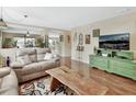 Inviting living room featuring hardwood floors, a cozy sofa, a large television, and views into the dining area at 1310 Pup Fish Ln, Deland, FL 32724