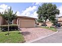 Beige home with a large garage, brick driveway, well maintained lawn, and mature trees at 201 Walter Stevens Way, Deland, FL 32724
