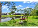 Serene backyard view of a bench overlooking a pond, lush greenery, and neighboring homes, creating a peaceful ambiance at 123 Wood Ibis Ct, Daytona Beach, FL 32119