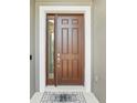 A traditional brown front door with sidelight and welcome mat, inviting entrance to the home at 1314 Lake Baton Dr, Deltona, FL 32725