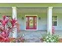 Inviting front porch featuring a stylish front door, beautiful landscaping, and red rocking chairs at 1383 Tumblin Dr, New Smyrna Beach, FL 32168