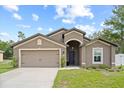 Inviting single-story home with a well-maintained lawn, two-car garage, and a welcoming arched entryway at 1846 N Acadian Dr, Deltona, FL 32725