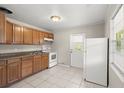 Traditional kitchen featuring wood cabinets, white appliances, and tile flooring at 2633 Yale Rd, South Daytona, FL 32119