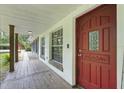 Inviting front porch featuring a vibrant red front door and rustic wood flooring at 2950 Ragis Rd, Edgewater, FL 32132