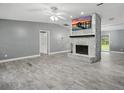 Open living room with a striking stone fireplace, vaulted ceilings, and wood-look tile flooring at 2950 Ragis Rd, Edgewater, FL 32132