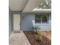 Home entryway featuring a white door, painted brick, small garden, and an outdoor light fixture at 3117 Pine Tree Dr, Edgewater, FL 32141