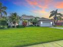 Lovely single-story home featuring lush green lawn, tropical palm trees, and attached two car garage at 456 Sea Duck Dr, Daytona Beach, FL 32119