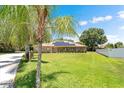 An attractive brick home with solar panels sits on a lush lawn, bordered by mature palm trees and shrubs at 519 Donaldson Dr, Debary, FL 32713