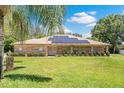 Charming brick home featuring a well-manicured lawn, complemented with solar panels for energy efficiency at 519 Donaldson Dr, Debary, FL 32713