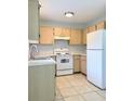 Functional kitchen features white appliances, light wood cabinets, and tile floors at 632 W Hubbard Ave, Deland, FL 32720