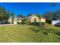 Lovely yellow home with lush green lawn, palm trees and well-maintained landscaping at 727 Grape Ivy Ln, New Smyrna Beach, FL 32168