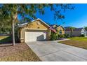 Garage of yellow single story home with driveway and well-maintained landscaping at 727 Grape Ivy Ln, New Smyrna Beach, FL 32168