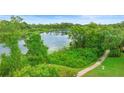 Lake view from the backyard with mature trees, lush vegetation, and walking path at 762 Onyx Pkwy, Deland, FL 32724