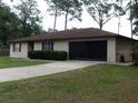 Classic single-story home with a two-car garage and a concrete driveway at 871 Oak Tree Ln, Lake Helen, FL 32744