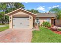 Charming single-story home showcasing a well-maintained lawn, brick driveway, and attached two-car garage at 118 Tuscany Villas Dr, Edgewater, FL 32141