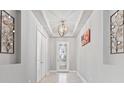 Bright foyer featuring decorative lighting, a tray ceiling, and a glass-paneled front door at 141 Mosaic Blvd, Daytona Beach, FL 32124