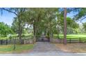 A gated entrance and driveway lined with mature trees create a private and welcoming approach at 1555 Mercers Fernery Rd, Deland, FL 32720