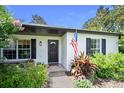 Inviting front entrance with decorative wreath, charming flower bushes, and an American flag at 1734 Magnolia Ave, Deland, FL 32724