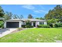 Charming single-story home featuring a lush green lawn, a tidy landscape, and a dark colored garage at 1734 Magnolia Ave, Deland, FL 32724