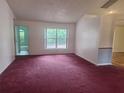 Spacious living room featuring red carpet, natural light, and neutral wall colors at 2051 Sherwood Forest Dr, Orange City, FL 32763