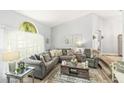 Bright living room featuring a large gray sectional, stylish decor, and a window showcasing a view of the trees at 2163 Fireside Rd, Deltona, FL 32738