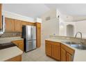 Modern kitchen with stainless steel refrigerator, tile backsplash, and wooden cabinets at 2478 Unionville Dr, Deltona, FL 32725