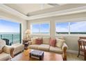 Comfortable living room featuring tile floors, tray ceiling, large windows with ocean views, and modern decor at 2801 Hill St # 801, New Smyrna Beach, FL 32169