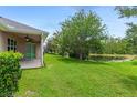 Spacious backyard features a covered patio, lush lawn, mature trees, and a tranquil pond view at 32 Abacus Ave, Ormond Beach, FL 32174
