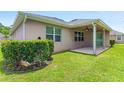 Backyard view with lush grass, partial view of patio with ceiling fan, and exterior wall with windows at 32 Abacus Ave, Ormond Beach, FL 32174