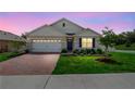 Charming single-story home featuring a well-manicured lawn, brick driveway, and blue shutters at 33436 Shutterfly Way, Sorrento, FL 32776