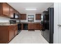 Well-equipped kitchen with black appliances, wooden cabinets, and tile flooring at 3810 Arboreal Ct, Deland, FL 32724