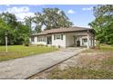 Well-maintained single-story home featuring a convenient carport and a driveway, complemented by lush greenery at 431 S Stone St, Deland, FL 32720