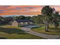 Sunset aerial view of stone facade home surrounded by mature trees and a long curving driveway at 5759 Dogwood Rd, Port Orange, FL 32127