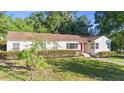 A cozy single-story house, featuring a well-manicured lawn and a charming red front door at 611 N Garfield Ave, Deland, FL 32724
